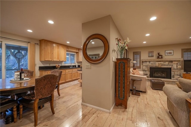 kitchen featuring light wood-type flooring, a fireplace, light brown cabinets, and sink