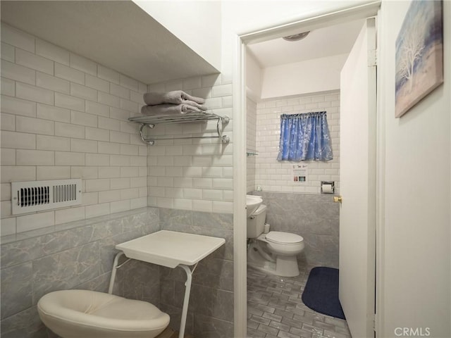 bathroom featuring toilet and tile walls