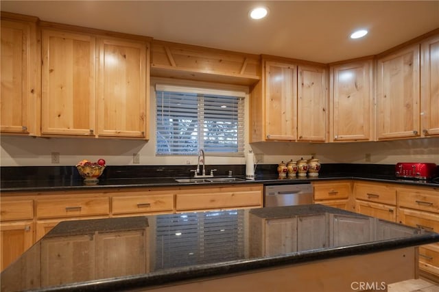 kitchen featuring light brown cabinetry, sink, stainless steel dishwasher, and dark stone countertops