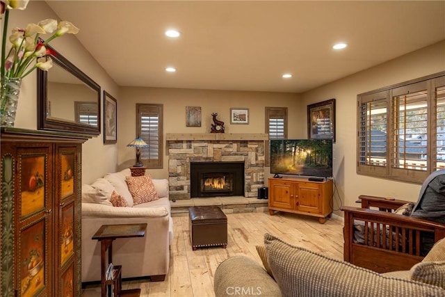 living room with a stone fireplace and light hardwood / wood-style flooring