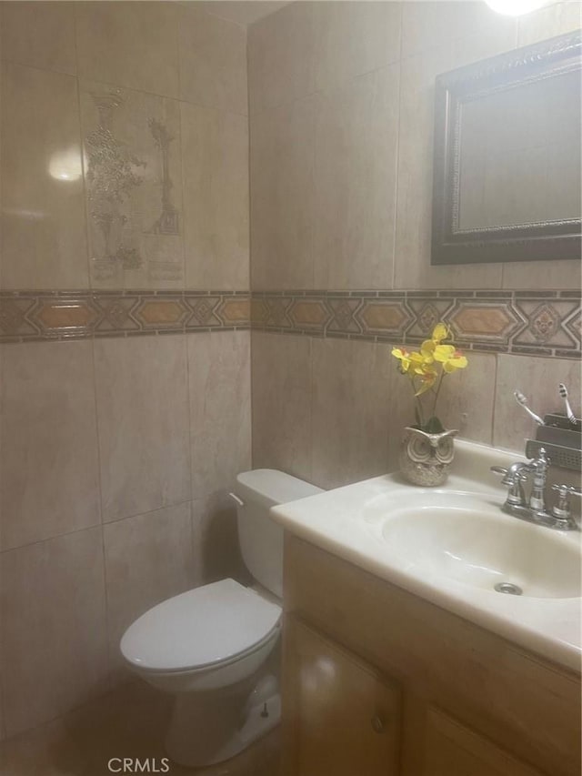 bathroom with vanity, toilet, tile walls, and backsplash