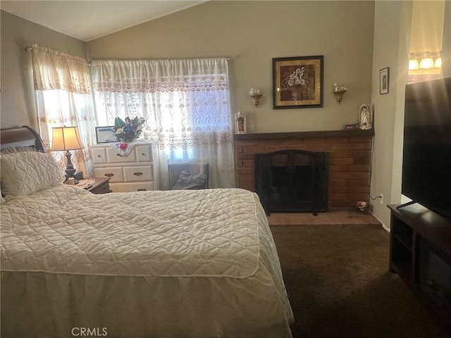 bedroom with lofted ceiling and a brick fireplace