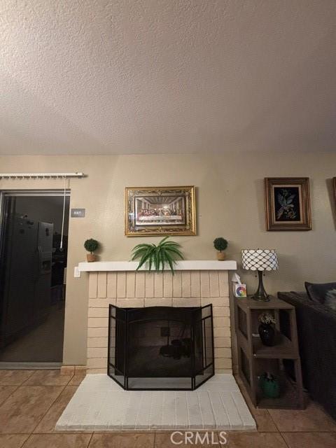 details featuring refrigerator with ice dispenser, a fireplace, and a textured ceiling