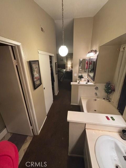 bathroom with vanity, a tub to relax in, and high vaulted ceiling