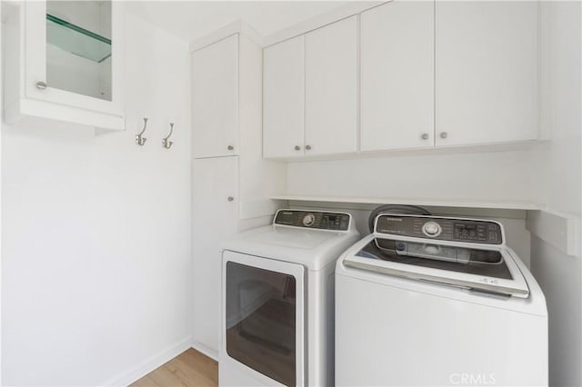 laundry area with independent washer and dryer, cabinets, and light hardwood / wood-style floors