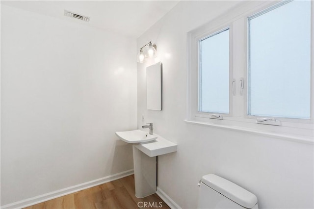 bathroom with toilet, wood-type flooring, and plenty of natural light