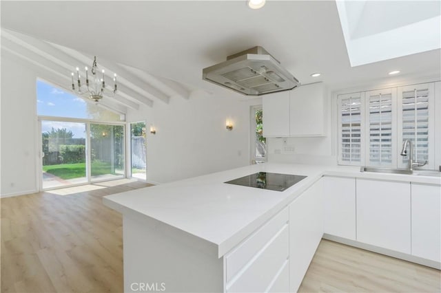 kitchen featuring white cabinets, kitchen peninsula, black electric cooktop, sink, and range hood