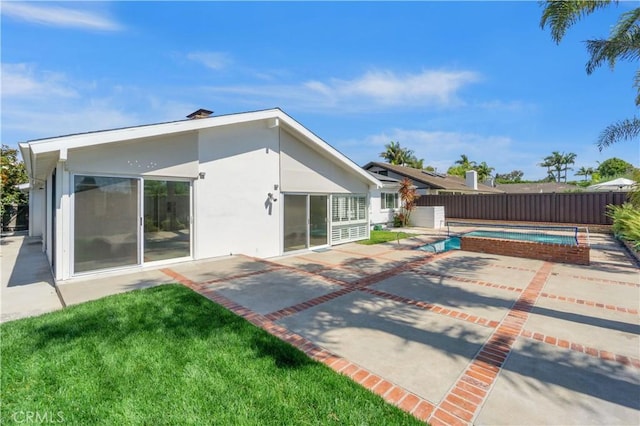 back of property with a lawn, a fenced in pool, and a patio area