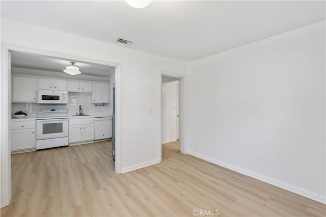 kitchen with white appliances, white cabinets, backsplash, and sink