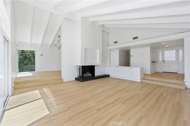 unfurnished living room featuring a brick fireplace, lofted ceiling with beams, and light hardwood / wood-style flooring