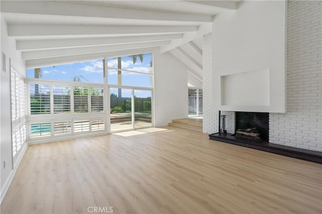 unfurnished living room featuring high vaulted ceiling, a brick fireplace, light wood-type flooring, and beam ceiling