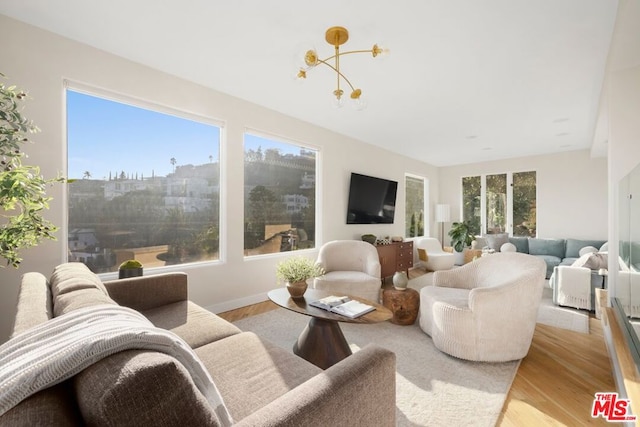 living room with plenty of natural light, light hardwood / wood-style flooring, and a chandelier