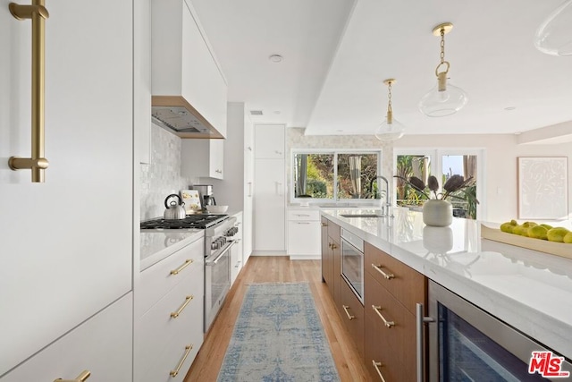 kitchen with sink, beverage cooler, white cabinets, and custom range hood