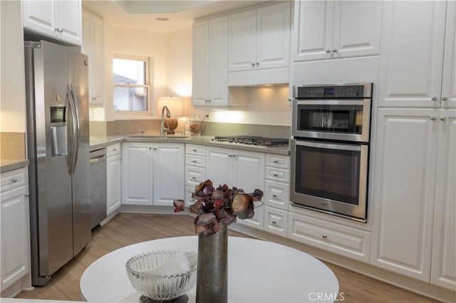 kitchen featuring white cabinets, sink, stainless steel appliances, and light hardwood / wood-style floors