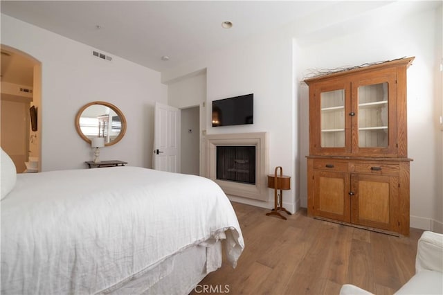 bedroom with connected bathroom and light hardwood / wood-style flooring