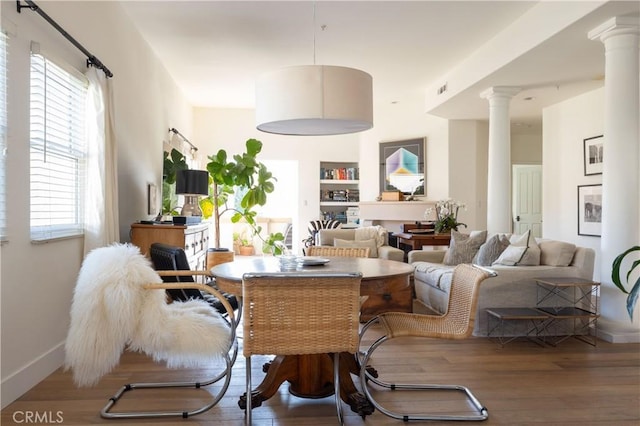 living room with wood-type flooring, built in shelves, and decorative columns