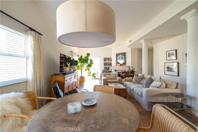 dining area featuring decorative columns, a wealth of natural light, and wood-type flooring