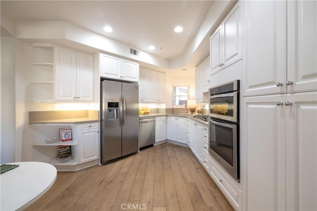 kitchen featuring light wood-type flooring, appliances with stainless steel finishes, white cabinetry, and sink