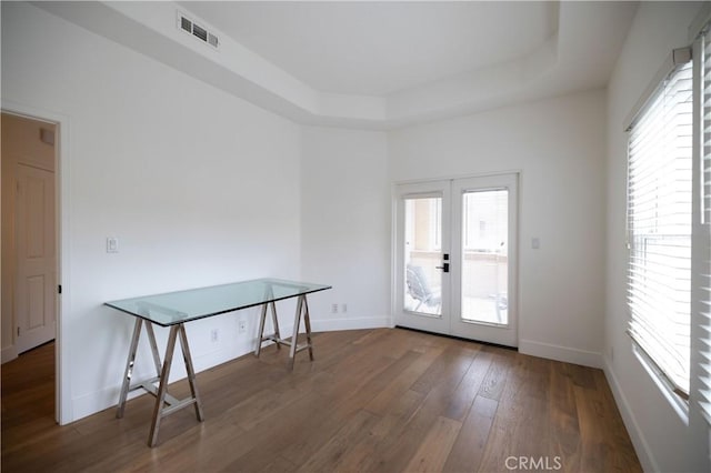 doorway to outside with hardwood / wood-style flooring, a raised ceiling, and french doors