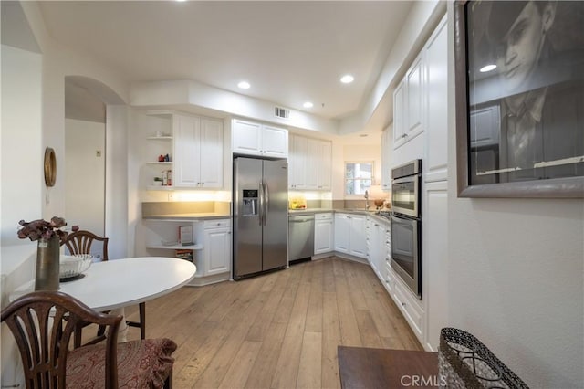 kitchen with appliances with stainless steel finishes, light hardwood / wood-style floors, white cabinets, and sink