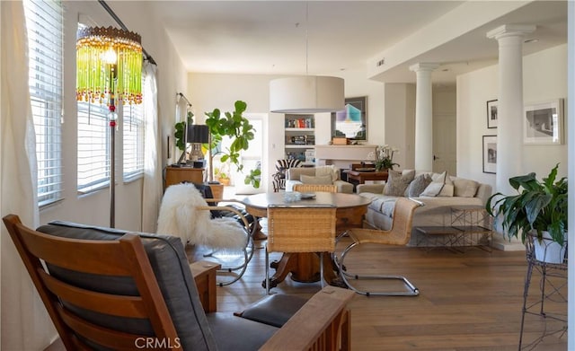 living room featuring a notable chandelier, ornate columns, and hardwood / wood-style floors