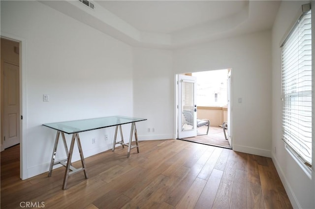 unfurnished room with hardwood / wood-style flooring and a raised ceiling