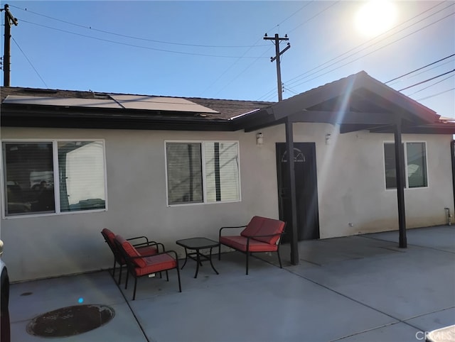 rear view of house with a shingled roof, a patio, and stucco siding