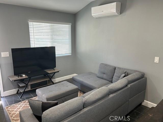 living area with dark tile patterned floors, baseboards, and a wall mounted AC