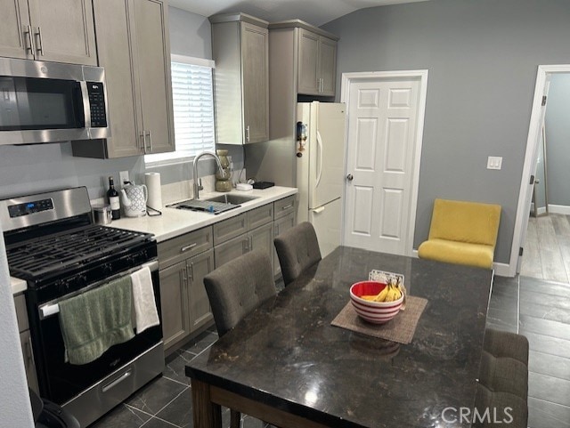 kitchen with lofted ceiling, appliances with stainless steel finishes, sink, and gray cabinets