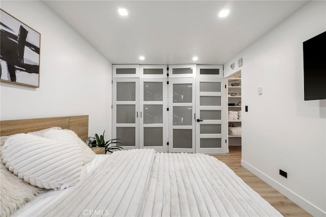 bedroom with recessed lighting, light wood-type flooring, and baseboards