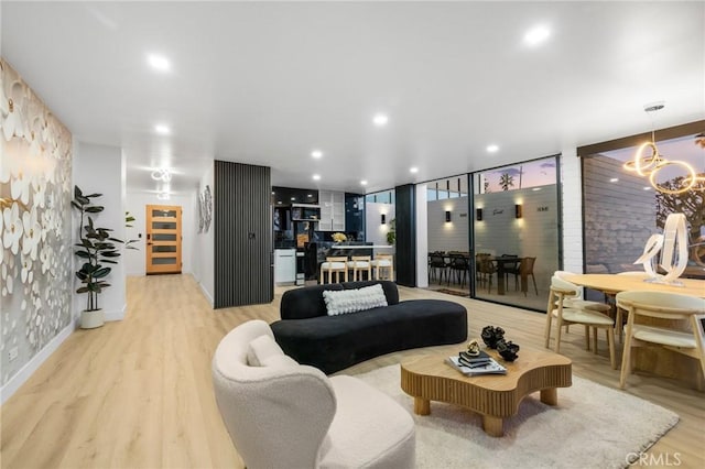 living room featuring light wood finished floors, recessed lighting, and an inviting chandelier