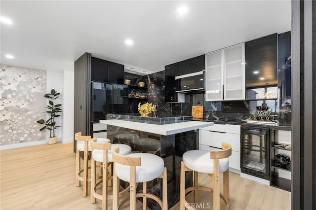 kitchen with wine cooler, light wood-style floors, modern cabinets, and a center island