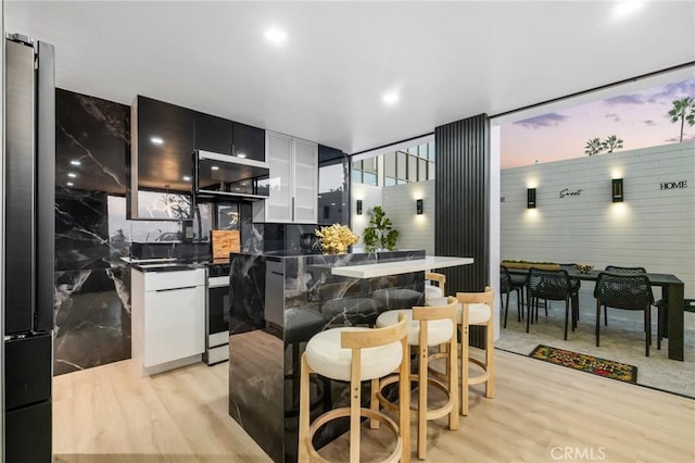 kitchen featuring a kitchen bar, dark countertops, modern cabinets, and light wood-style flooring