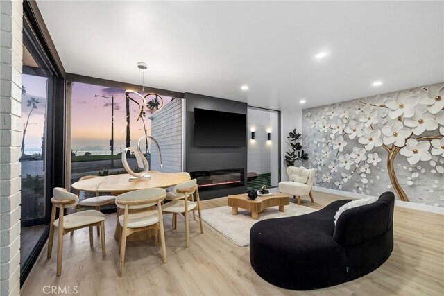 dining space with a large fireplace, a notable chandelier, floor to ceiling windows, and light hardwood / wood-style flooring