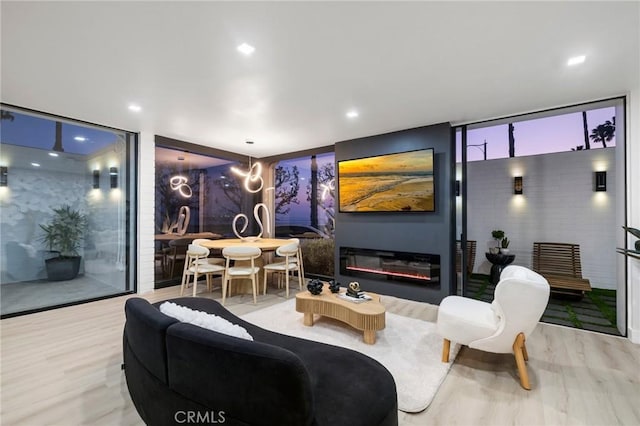 living area with a glass covered fireplace, wood finished floors, and expansive windows