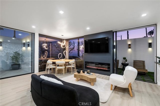 living room featuring a glass covered fireplace, expansive windows, and wood finished floors