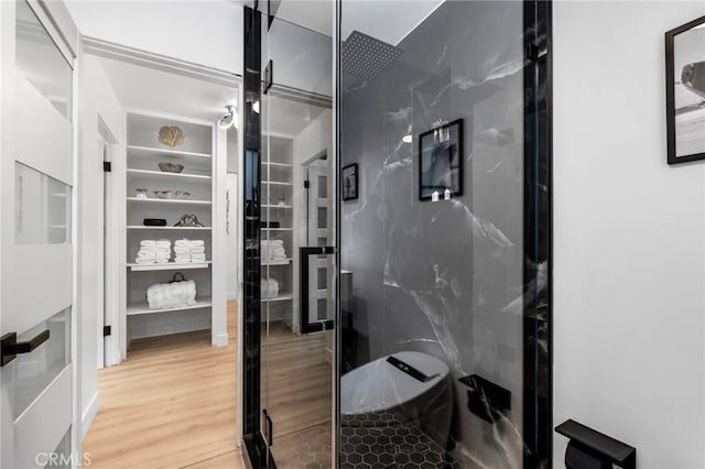 bathroom with wood finished floors and a marble finish shower