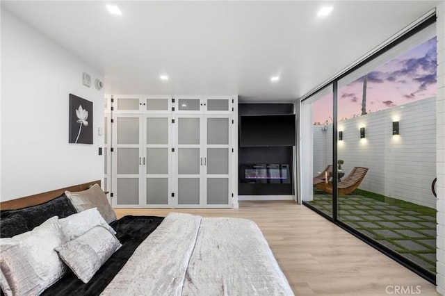 bedroom featuring recessed lighting, expansive windows, and wood finished floors