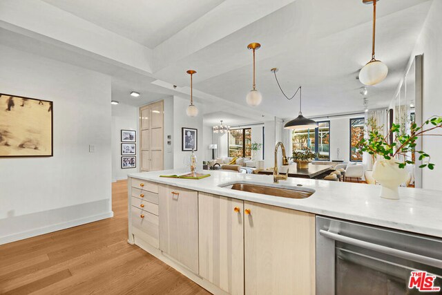 kitchen featuring dishwasher, pendant lighting, sink, light wood-type flooring, and a chandelier