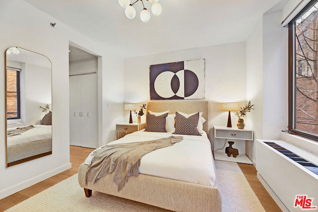 bedroom featuring radiator, a chandelier, and hardwood / wood-style flooring