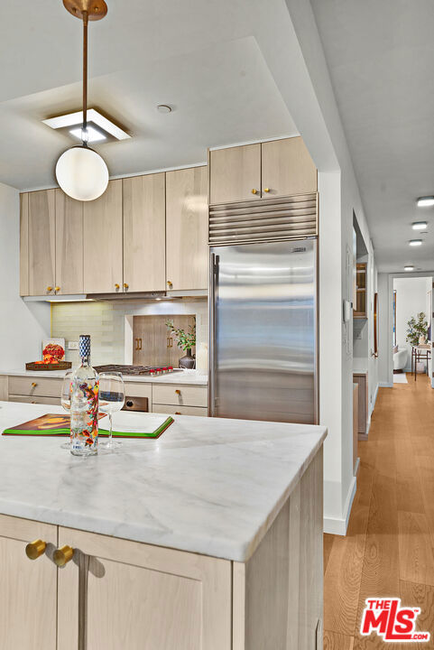 kitchen featuring built in refrigerator, light hardwood / wood-style flooring, light brown cabinets, and backsplash