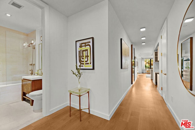 hallway with sink and light wood-type flooring