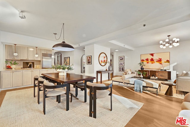 dining area with light wood-type flooring and a notable chandelier