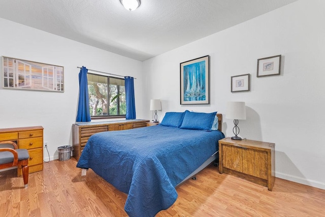 bedroom with a textured ceiling and light hardwood / wood-style flooring