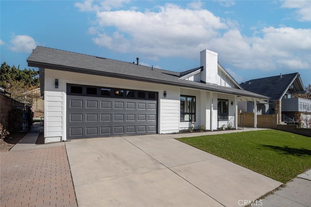 single story home with a garage, a front lawn, and a porch