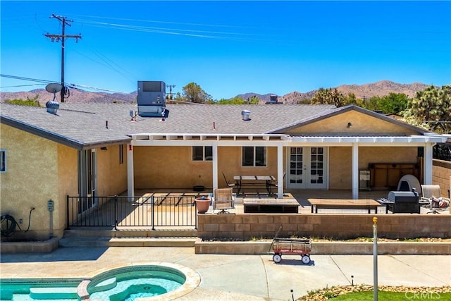 rear view of property featuring central AC unit, an in ground hot tub, french doors, a patio, and a mountain view