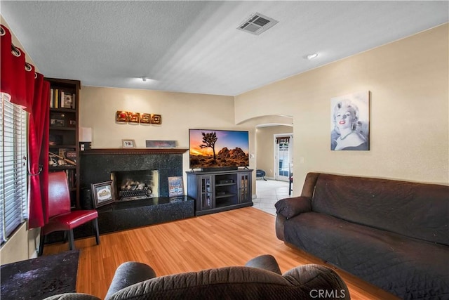 living room featuring a tile fireplace, a textured ceiling, and hardwood / wood-style flooring