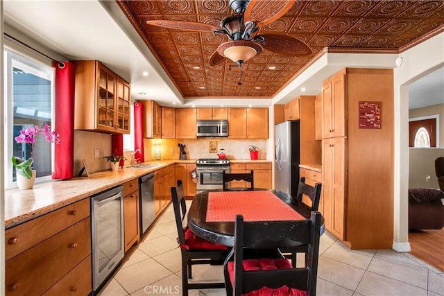 kitchen featuring ceiling fan, appliances with stainless steel finishes, a healthy amount of sunlight, and wine cooler