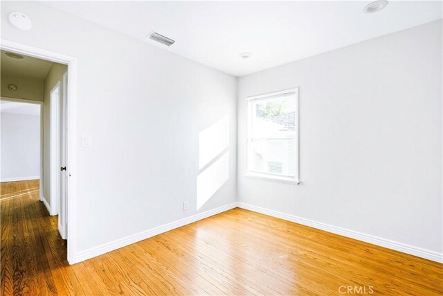 empty room with visible vents, baseboards, and wood finished floors