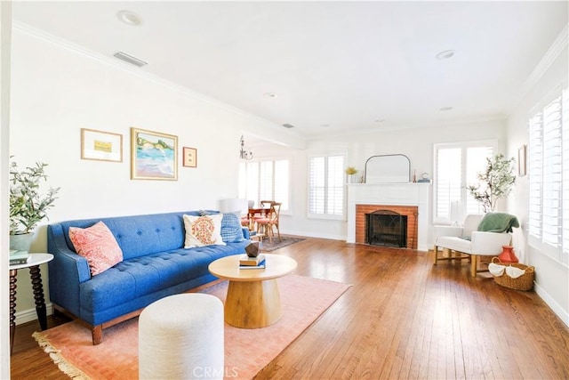 living room featuring a wealth of natural light, hardwood / wood-style floors, crown molding, and a fireplace